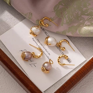 Elegant natural baroque pearl earrings with gold hooks on a vintage card background