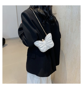 Sac papillon argenté avec strass et chaîne dorée porté sur un blazer noir élégant
