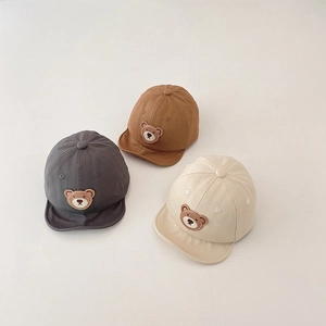 Detailed top view of soft infant baseball caps in grey, brown and beige with bear patches