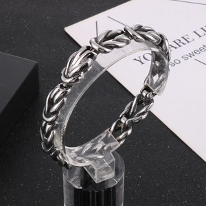 Macro detail of silver knot chain bracelet with woven design on acrylic stand