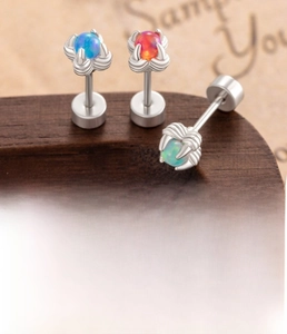 Macro detail of titanium dragon claw earrings featuring opal stones in red, blue, and green