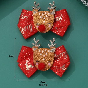 Detail of red Christmas reindeer bow hair clips with glitter accents on green background