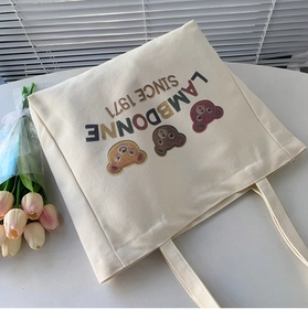 Detail of off-white canvas tote bag featuring cute cartoon bear digital prints and straps