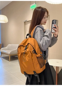 Detailansicht eines orangefarbenen Rucksacks mit seitlicher Netztasche und Kordelzug-Detail