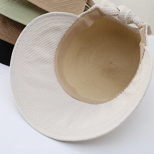 Detail of straw sun hat featuring a large decorative bow and inner sweatband