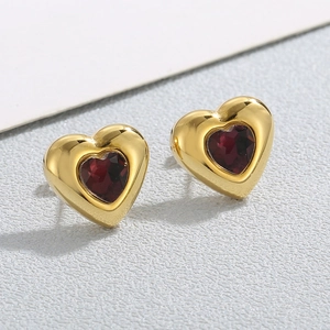 Vista macro di orecchini a cuore placcati in oro con intarsio in cristallo rosso