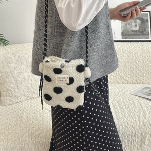 Close-up of plush polka dot shoulder bag with woven rope strap and snap button closure