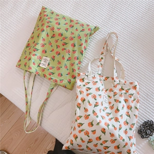 Flachliegende Detailaufnahme von grünen und beigen Stofftaschen mit Tulpen-Blumenmuster