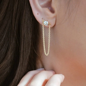 Detailed close-up of a long golden chain earring with a sparkling cubic zirconia stone