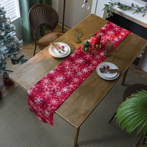 Red Christmas table runner with snowflake patterns on a rustic wooden dining table