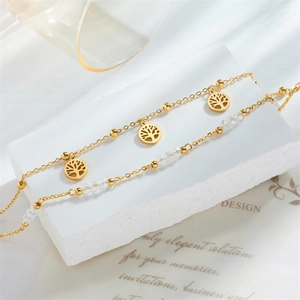 Luxurious gold tree of life anklet with faceted crystal beads on white marble surface