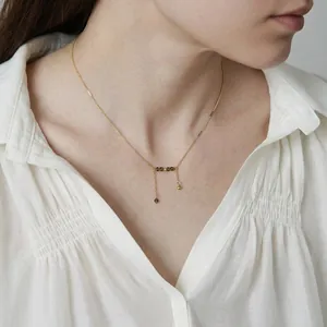 Elegant 18K gold plated titanium necklace with olive green crystal beads on white shirt