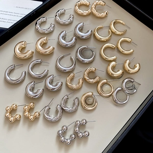 Close-up of various C-shape hoop earrings with smooth, twisted, and beaded metal textures