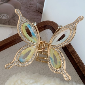 Close-up of golden butterfly hair claw with marble pattern and sparkling rhinestones