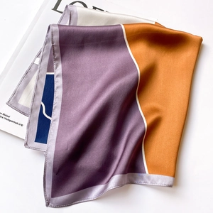 Artistic fold of silk scarf featuring purple and orange geometric patterns on white background