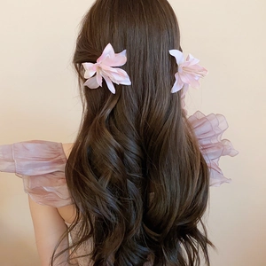 Close-up of pink fabric hibiscus flower hair clips on long wavy brown hair
