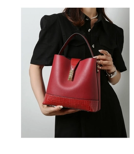 Detail of red bucket bag with crocodile embossed texture and golden metal buckle