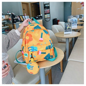 Close-up of yellow children's backpack with floral prints and a cute frog badge accessory