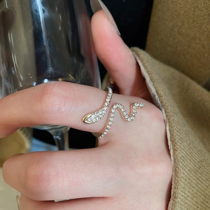 Close-up of a gold snake-shaped ring with sparkling crystals on a woman's finger