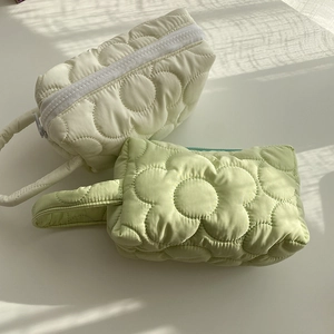 Detail of floral quilted polyester makeup bags in cream and mint with zipper closure