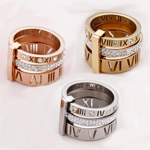 Detailed view of three stackable rings in gold, rose gold, and silver with Roman numerals