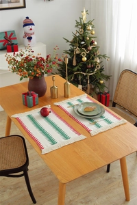 Close-up of woven cotton linen Christmas placemats with red green trees and fringes