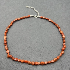 Detailed close-up of natural red jasper irregular stone necklace with silver lobster clasp