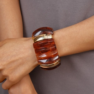 Detail of wide geometric bracelet featuring amber resin blocks and polished gold metal parts
