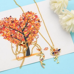 Macro detail of gold-plated flamingo and toucan pendants with colorful cubic zirconia