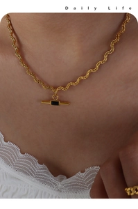 Detailed shot of golden rope chain necklace featuring a rectangular black gemstone pendant
