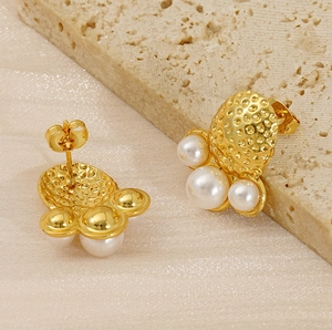 Detail of gold-plated hammered texture earrings with elegant white pearls on stone