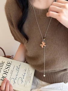 Detail of silver rocking horse pendant with pearl accent on long brown leather cord necklace