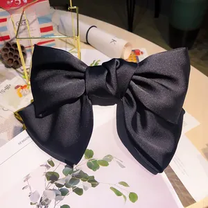 Close-up of oversized black satin bow hair clip with elegant double-layer silk texture