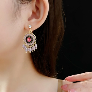 Detail of vintage gold flower earring with pink crystal center and purple teardrop beads
