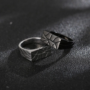 Detailed view of square engraved geometric patterns on silver and black steel rings