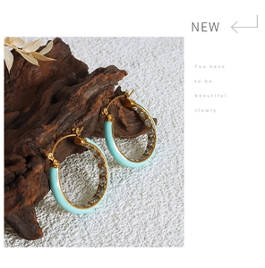 Macro detail of light blue enamel hoop earring with paved white zircons and gold plating