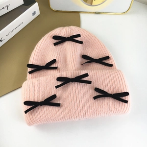 Pink knit rabbit fur hat with black bows and warm ear protection for women in winter