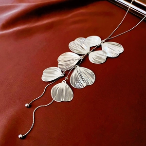 Makroansicht der silbernen Ginkgoblatt-Halskette mit Metalltexturen und Quasten-Details