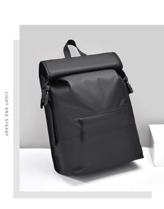 Detail view of black roll-top waterproof nylon backpack with front zipper and side buckles