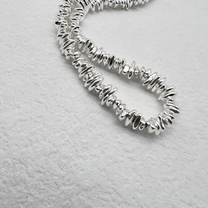 Detailed macro view of irregular polished silver beads on a minimalist stone necklace