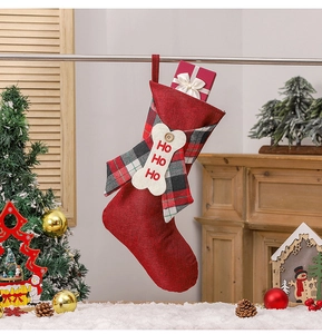 Detail of red Christmas stocking with plaid bow, bone ornament and HO HO HO embroidery