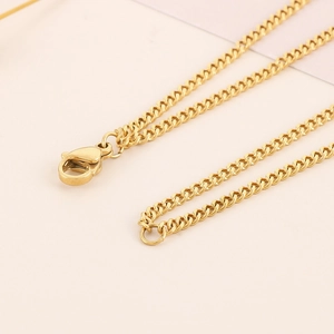 Close-up of golden Cuban link necklace with lobster clasp on pink background