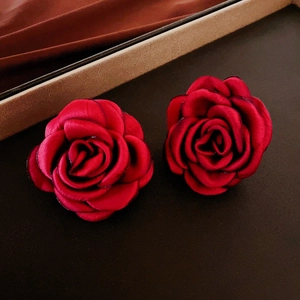 Detailed macro view of red flocked rose earrings with delicate silk fabric texture