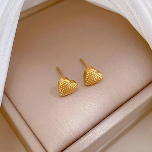 Minimalist gold heart stud earrings with lattice pattern in jewelry box with white satin