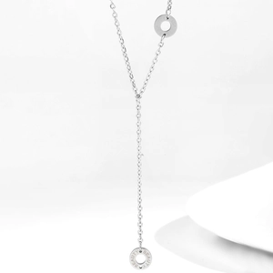 Dettaglio di una collana a Y argento con due pendenti rotondi incisi con BEAUTY