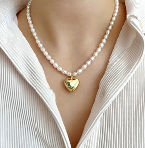 Detail of 925 sterling silver heart pendant necklace with elegant white pearls on a model