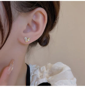Detail of heart stud earring with micro-pave diamonds and pearl on female ear