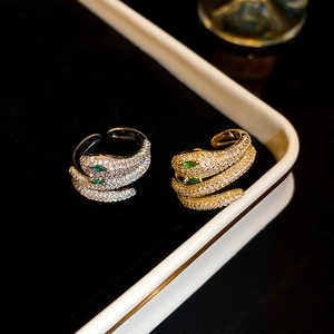 Detailed macro view of snake-shaped rings with green stone eyes and white zircon stones