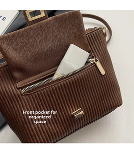 Detail of front pocket on brown pleated crossbody bag showing storage for cosmetics
