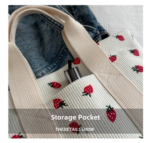 Detail of corduroy tote bag with strawberry print showing a functional front storage pocket